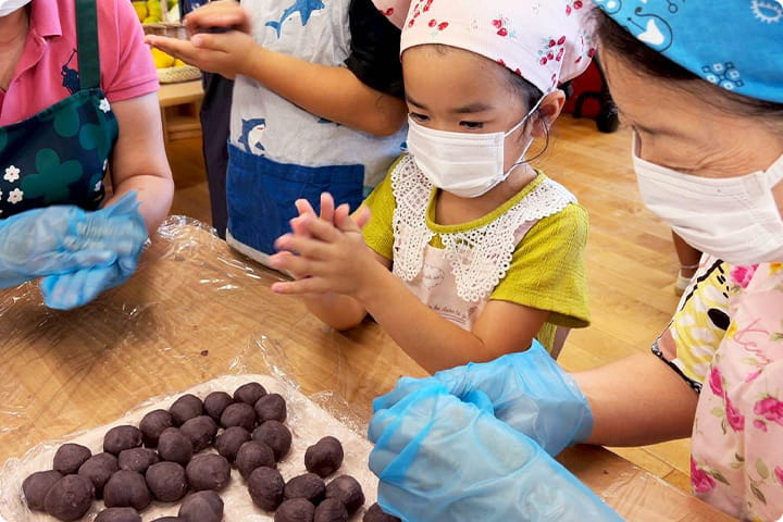 マスクと三角巾を着用し、調理を楽しむ子どもたち