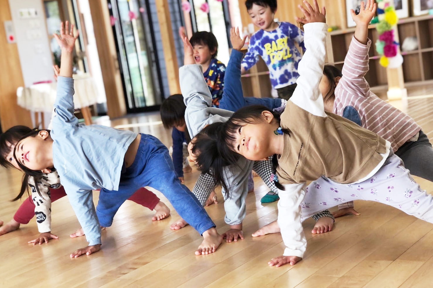 室内で子どもたちが体を伸ばしながら、元気にストレッチ運動をしている様子
