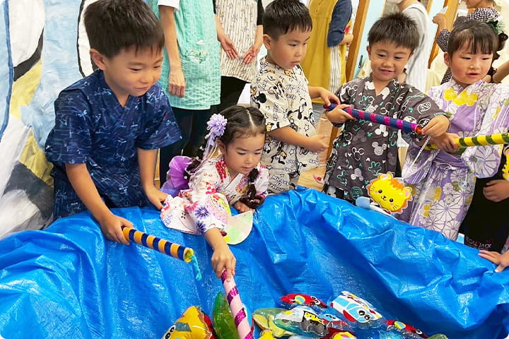 夏祭りで浴衣を着た子どもたちが、釣り遊びを楽しんでいる様子