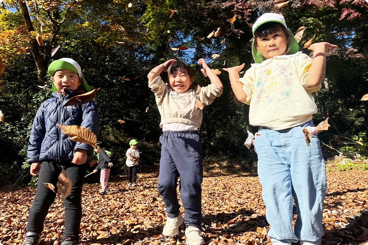公園で子どもたちが落ち葉を投げて遊ぶ