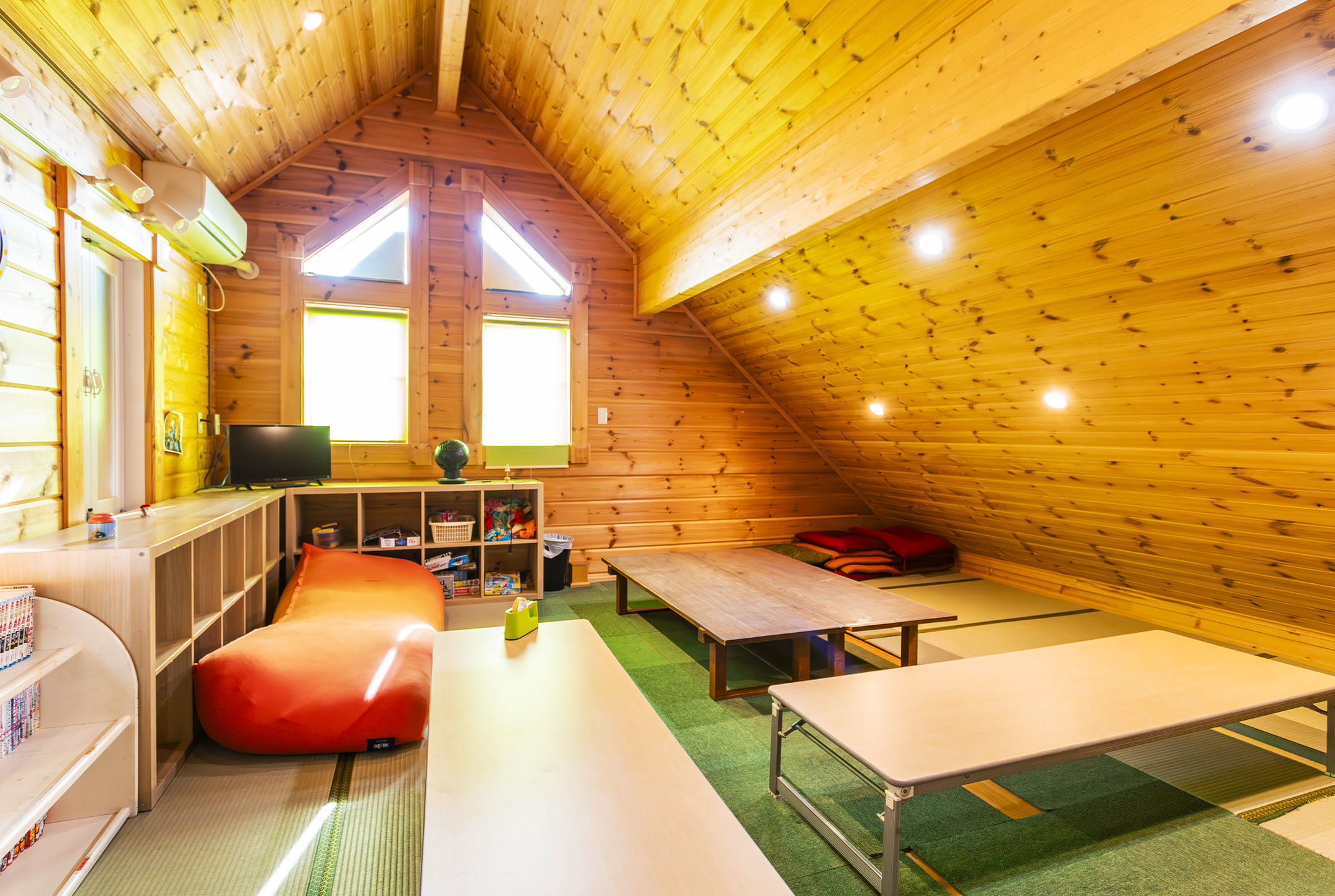 木の温もりあふれる屋根裏風の室内。畳や低いテーブルが並び、落ち着いた雰囲気のくつろぎ空間