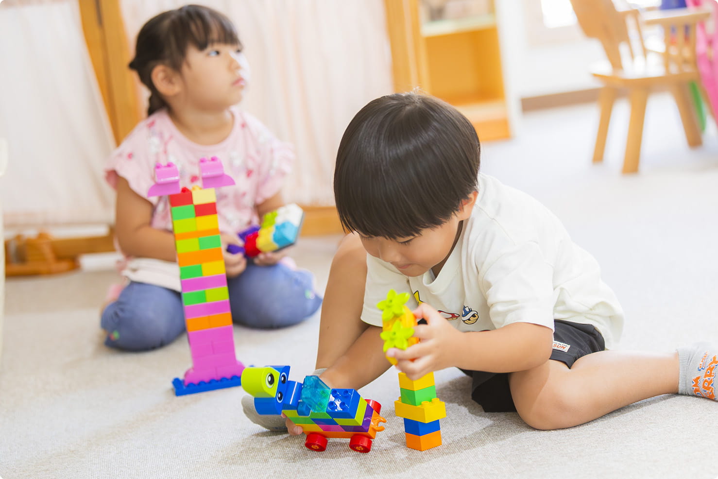 室内でブロック遊びをする子どもたちが集中して作品を作っている様子