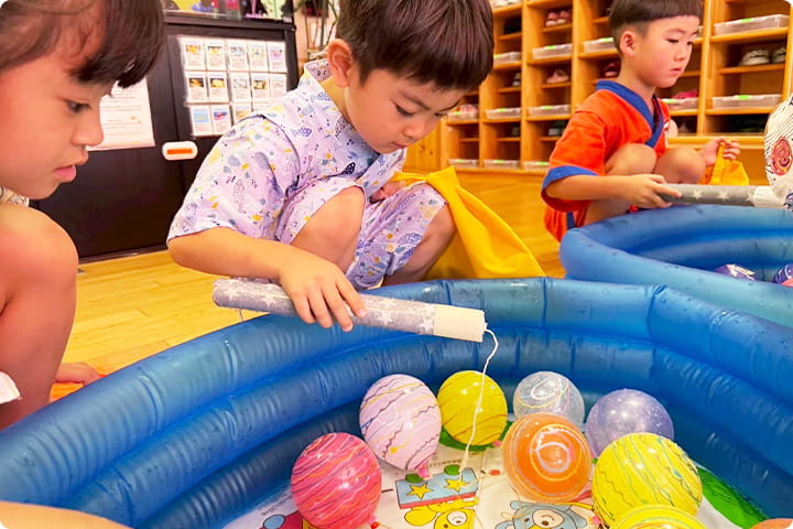 浴衣姿の子どもたちがヨーヨー釣りを楽しんでいる