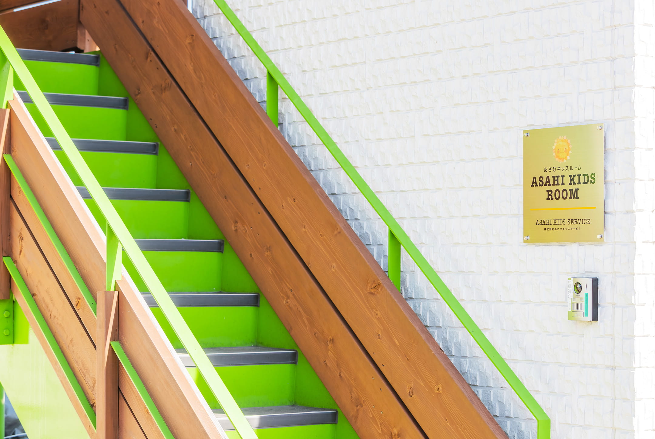 外階段の横に「あさひキッズルーム」の看板が掲げられている建物入口